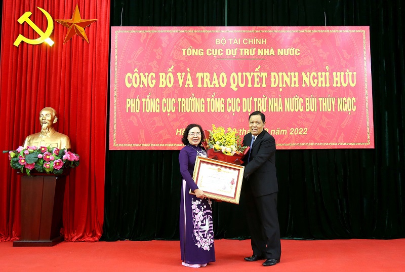 Tổng cục trưởng Tổng cục DTNN Đỗ Việt Đức trao Huân chương Lao động hạng Nhì và tặng hoa chúc mừng đồng chí Bùi Thúy Ngọc.