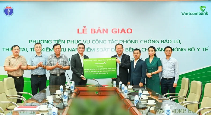 Đại diện Vietcombank là ông Nguyễn Việt Cường - Phó Tổng Giám đốc (thứ 4 từ phải sang) và đại diện Bộ Y tế là ông Hà Anh Đức - Chánh Văn phòng Bộ Y tế (thứ 4 từ trái sang) thực hiện nghi thức trao gói an sinh xã hội