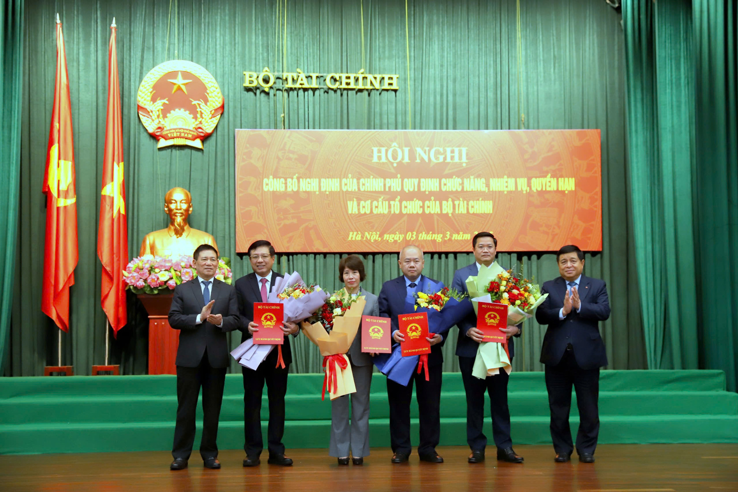 Phó Thủ tướng Chính phủ Hồ Đức Phớc và Phó Thủ tướng Chính phủ Nguyễn Chí Dũng trao quyết định và tặng hoa chúc mừng các Thứ trưởng Bộ Tài chính. Ảnh: L. Trường
