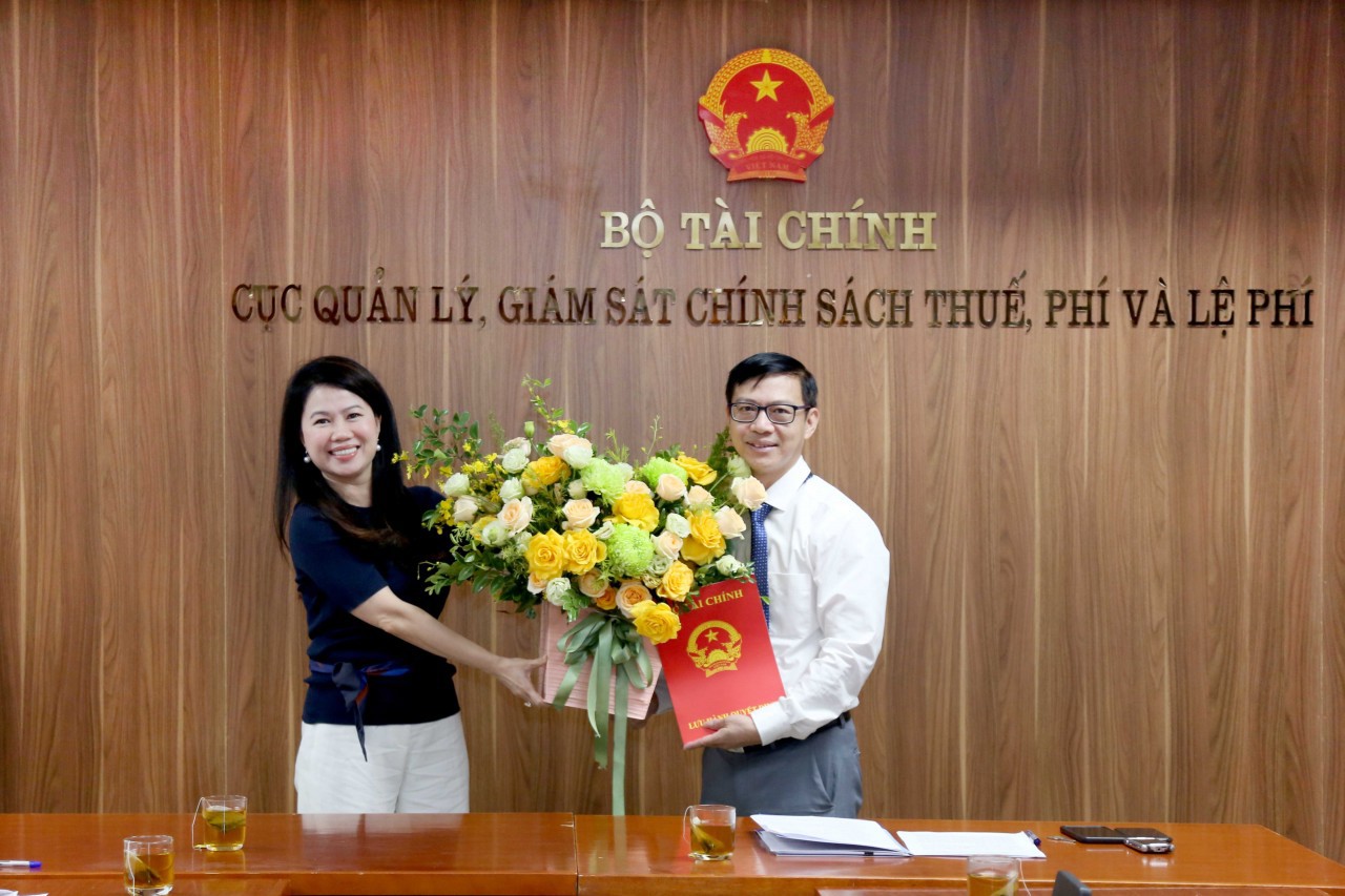 Bà Trần Thị Minh Hiền - Cục trưởng Cục Quản lý, giám sát chính sách thuế, phí và lệ phí trao Quyết định và tặng hoa cho ông Trương Huỳnh Thắng.