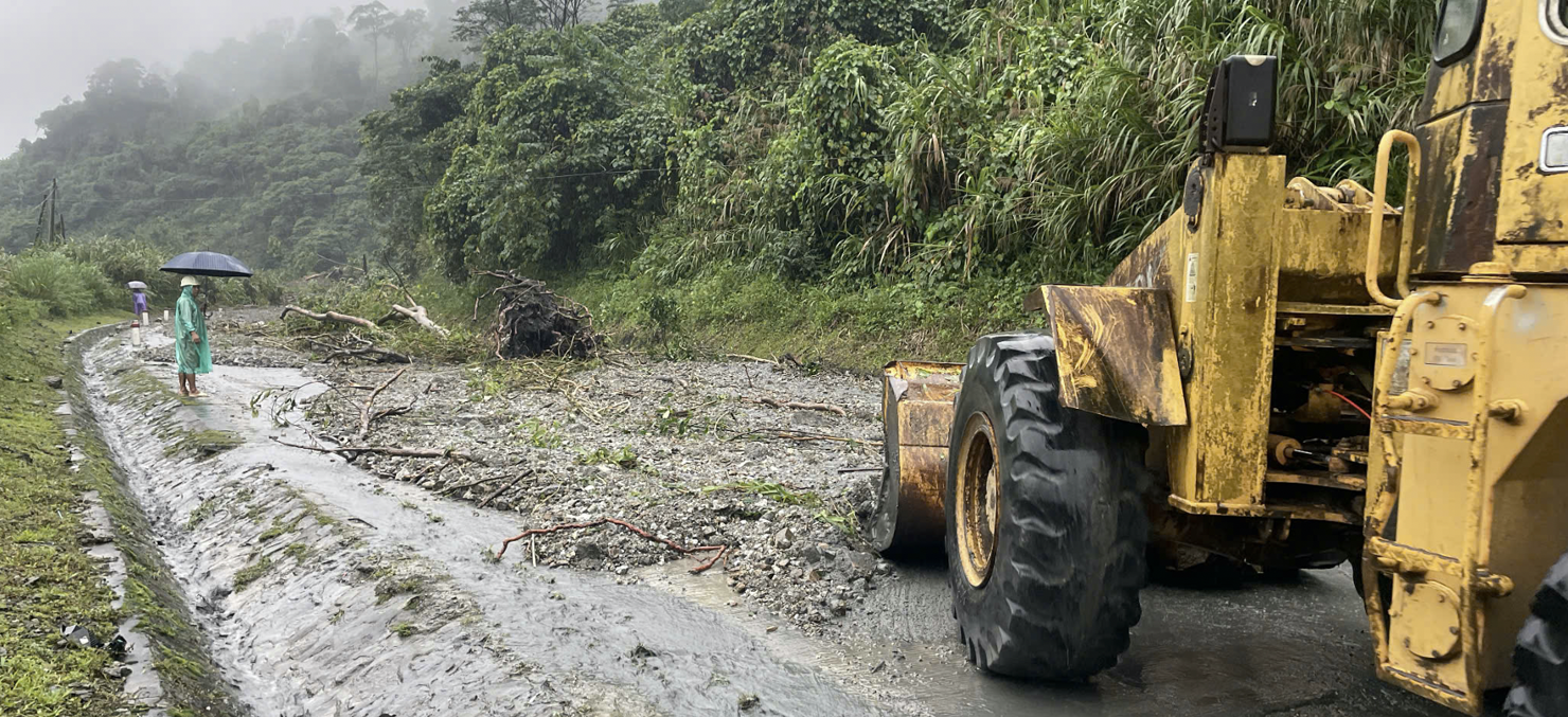 Lực lượng chức năng huy động máy móc, nhân lực hót dọn đất, đá tràn xuống mặt đường tại Km1407+800 đường Hồ Chí Minh