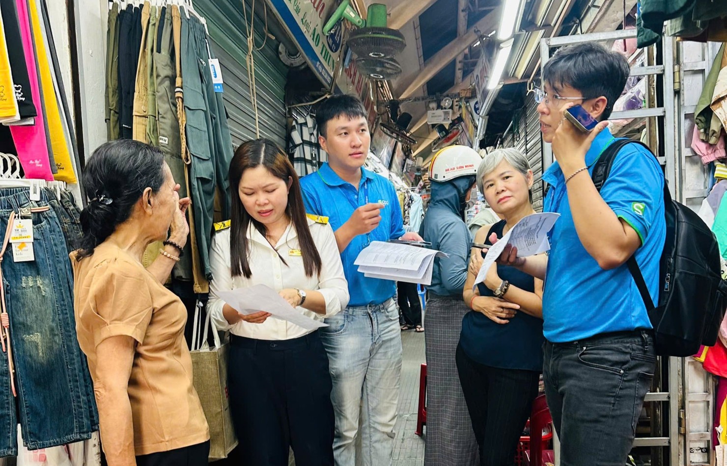 Cán bộ thuế cùng đơn vị cung cấp giải pháp hỗ trợ tận nơi hộ kinh doanh sử dụng ứng dụng eTax Mobile. Ảnh: TL